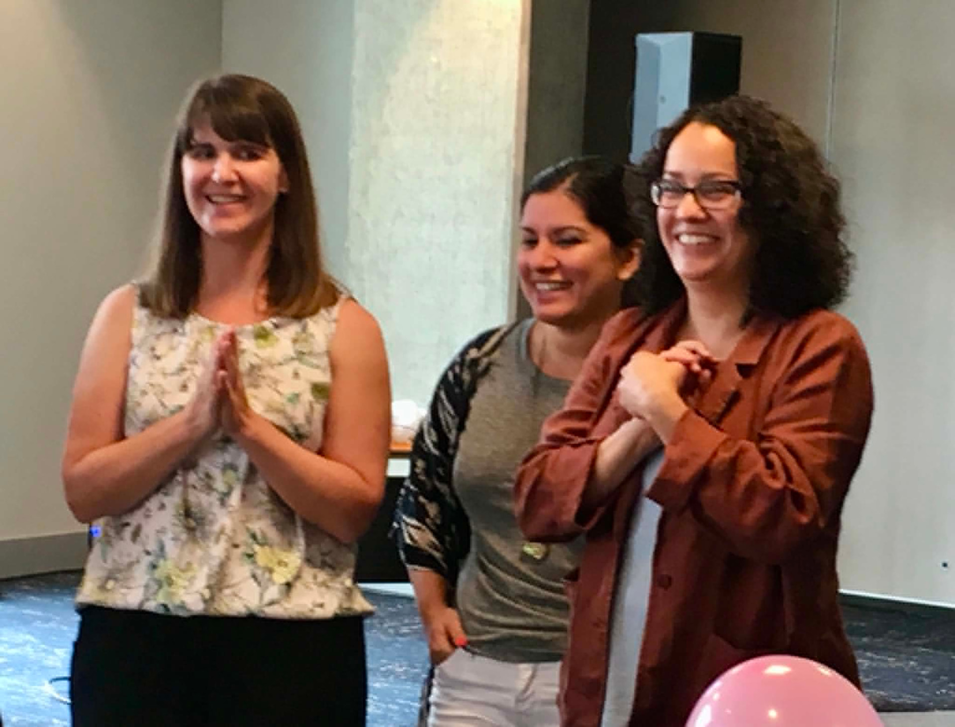 Three Academy participants smiling and applauding during a celebration