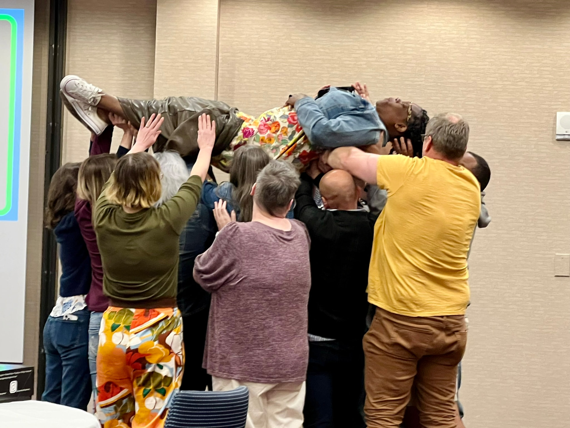 Academy participants lifting a colleague into the air in a trust-building celebration