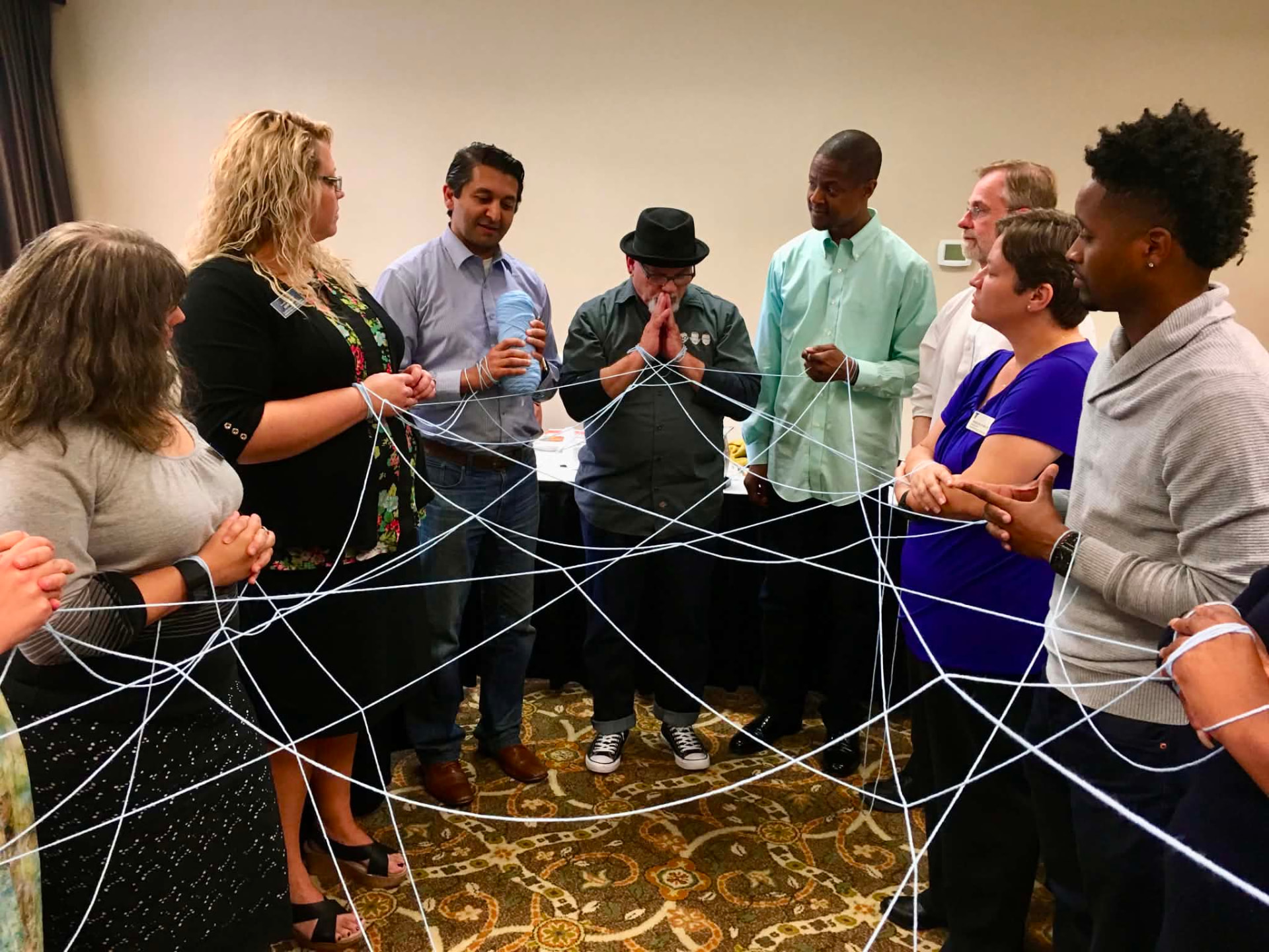 An Academy cohort standing in a circle holding a web of string during a connection activity