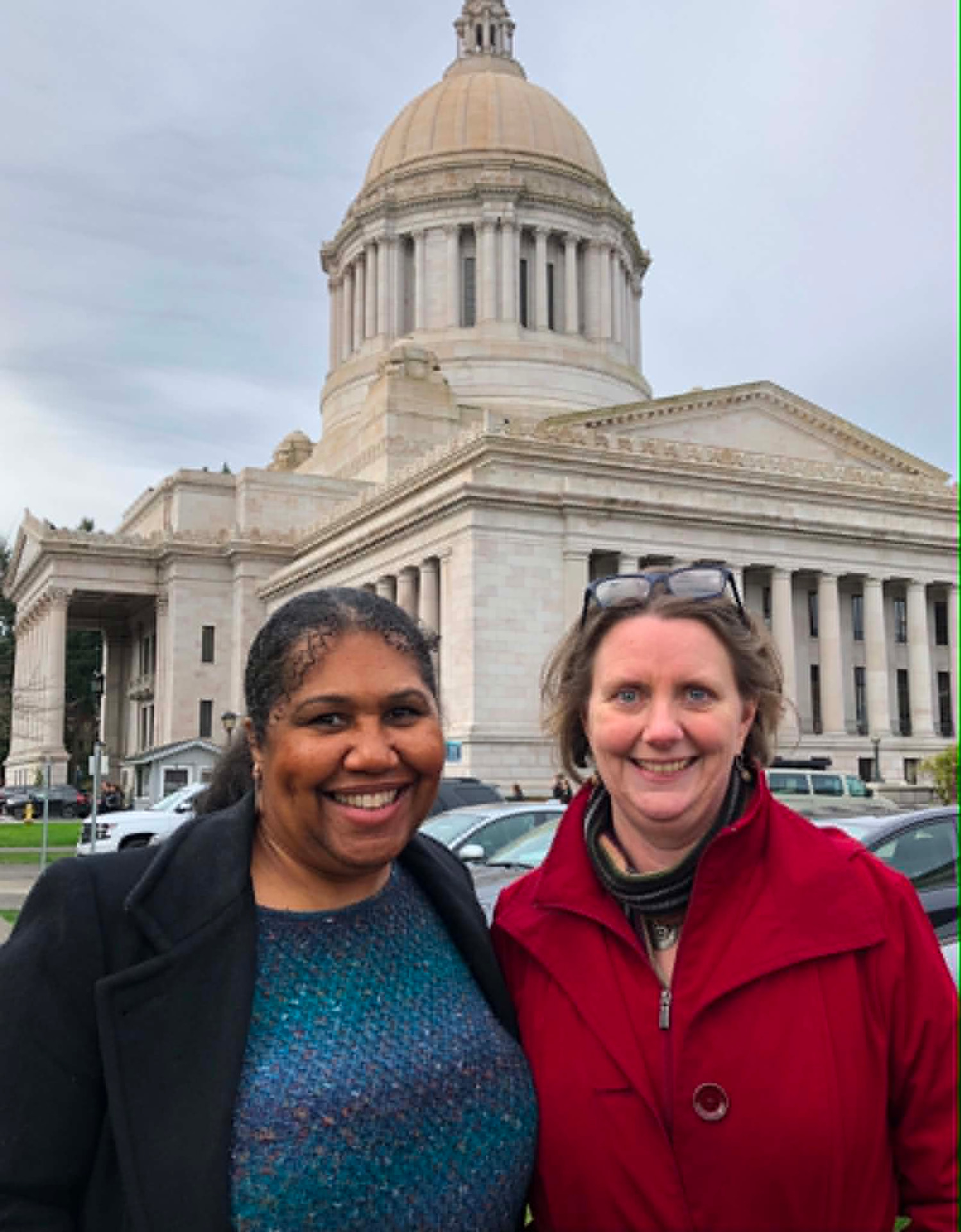 Two Academy participants, including one wearing red, standing outside the Washington State Capitol