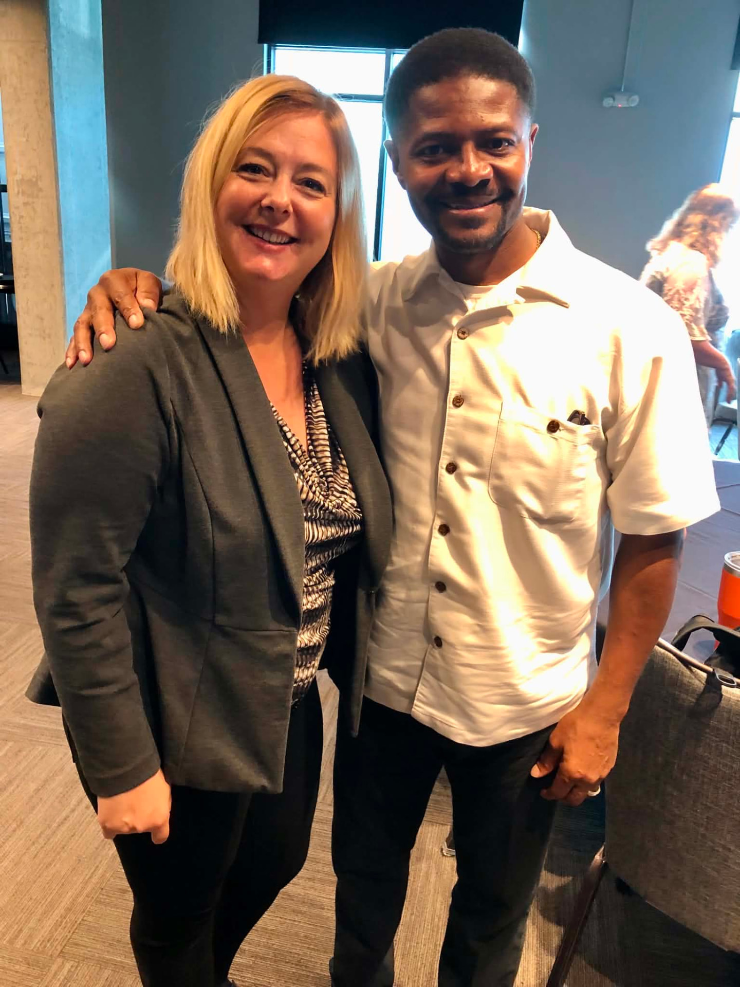 Two Academy colleagues standing arm in arm and smiling at a session