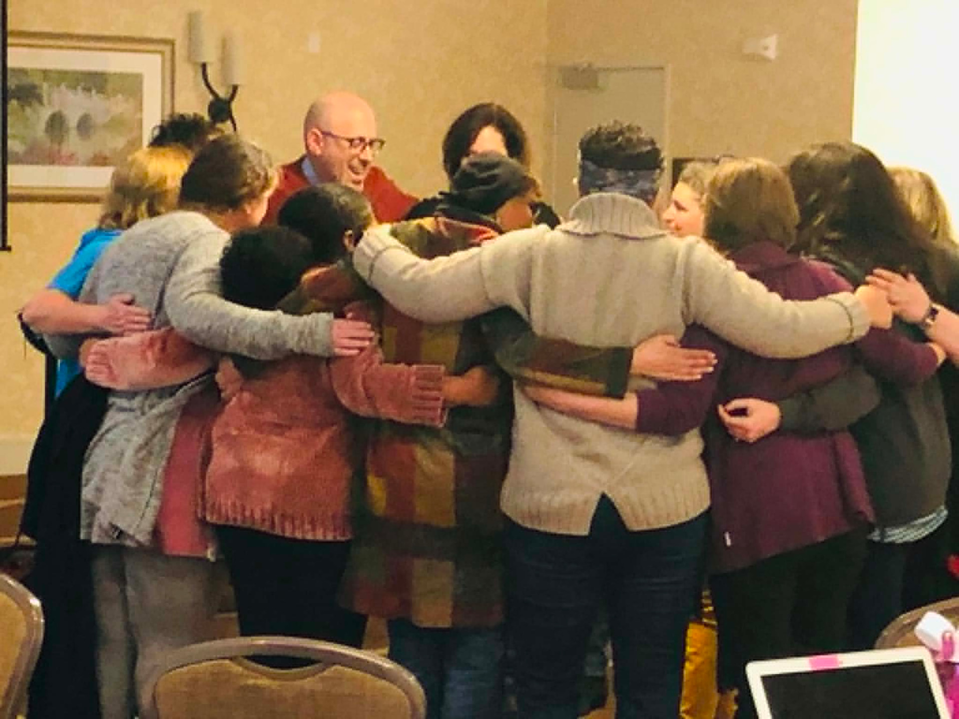 Academy cohort standing arm in arm in a closing huddle