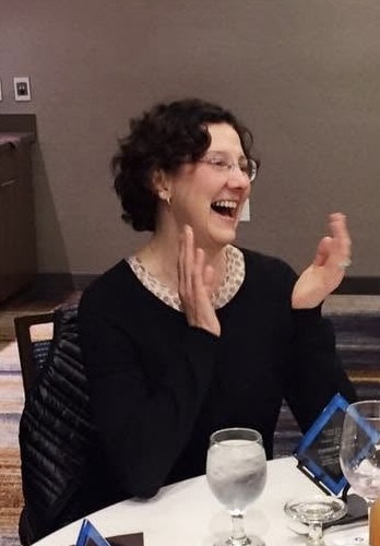 An Academy participant in glasses laughing during a cohort dinner
