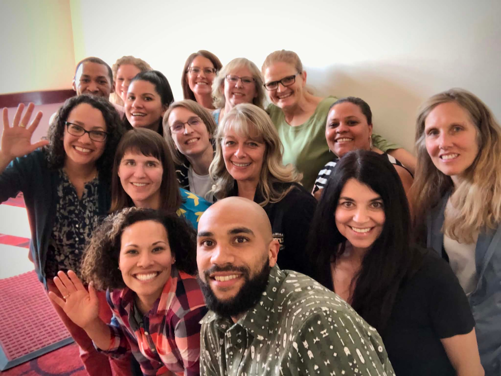 An Academy cohort crowded together waving for a group selfie