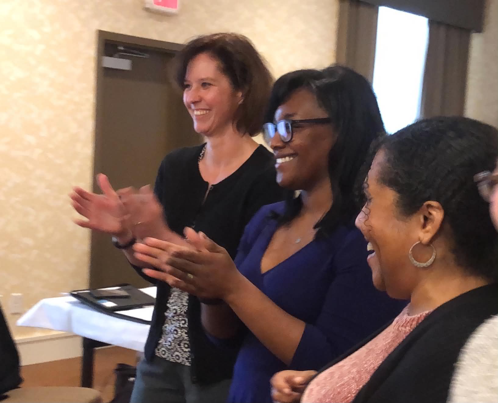 Three Academy participants applauding during a session