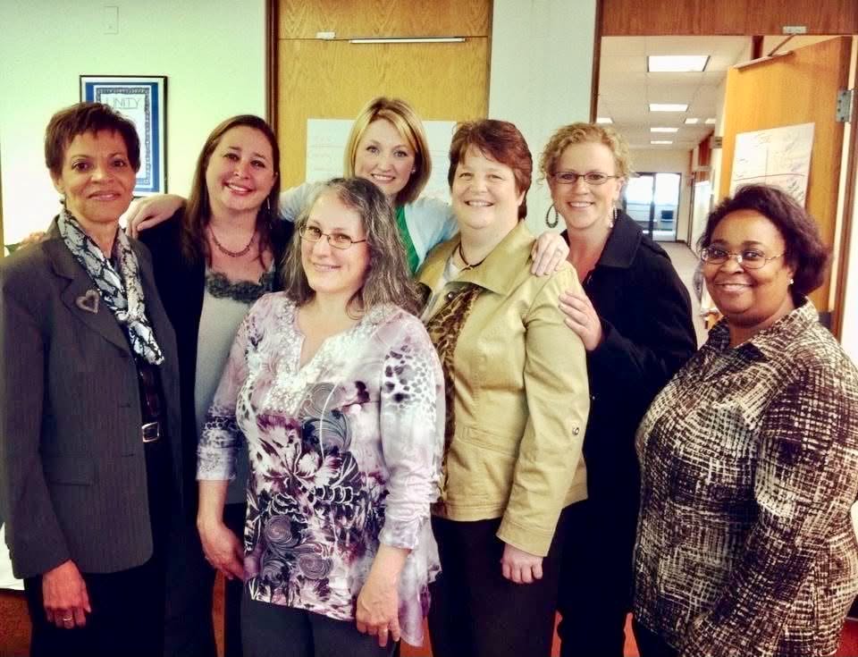 Seven Academy participants gathered together in a hallway between sessions